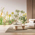 Botanical wallpaper mural featuring delicate South African flora and wildflowers in soft natural tones, with trailing greenery overhead and illustrated aloe, fynbos, and meadow plants across a light background. On a wall in a waiting area.
