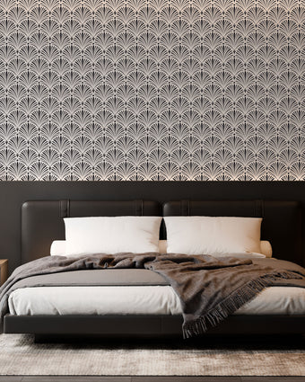 Art Deco wallpaper with repeating shell motifs in a black and off-white monochrome pattern. On bedroom wall behind bed. 