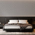Art Deco wallpaper with repeating shell motifs in a black and off-white monochrome pattern. On bedroom wall behind bed. 