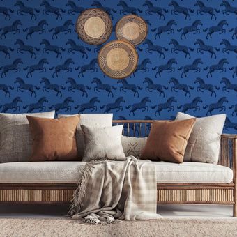 Repeating zebra wallpaper pattern featuring navy and royal blue zebras on a cobalt blue background. Wallpaper in a safari longe seating area, be hide the couch. 