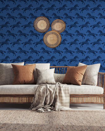Repeating zebra wallpaper pattern featuring navy and royal blue zebras on a cobalt blue background. Wallpaper in a safari longe seating area, be hide the couch. 