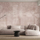 Blush toned forest mural featuring misty woodland trees and soft layered foliage in a dreamy, watercolour inspired style. On a wall in a lounge, behind the beige/cream couch. 