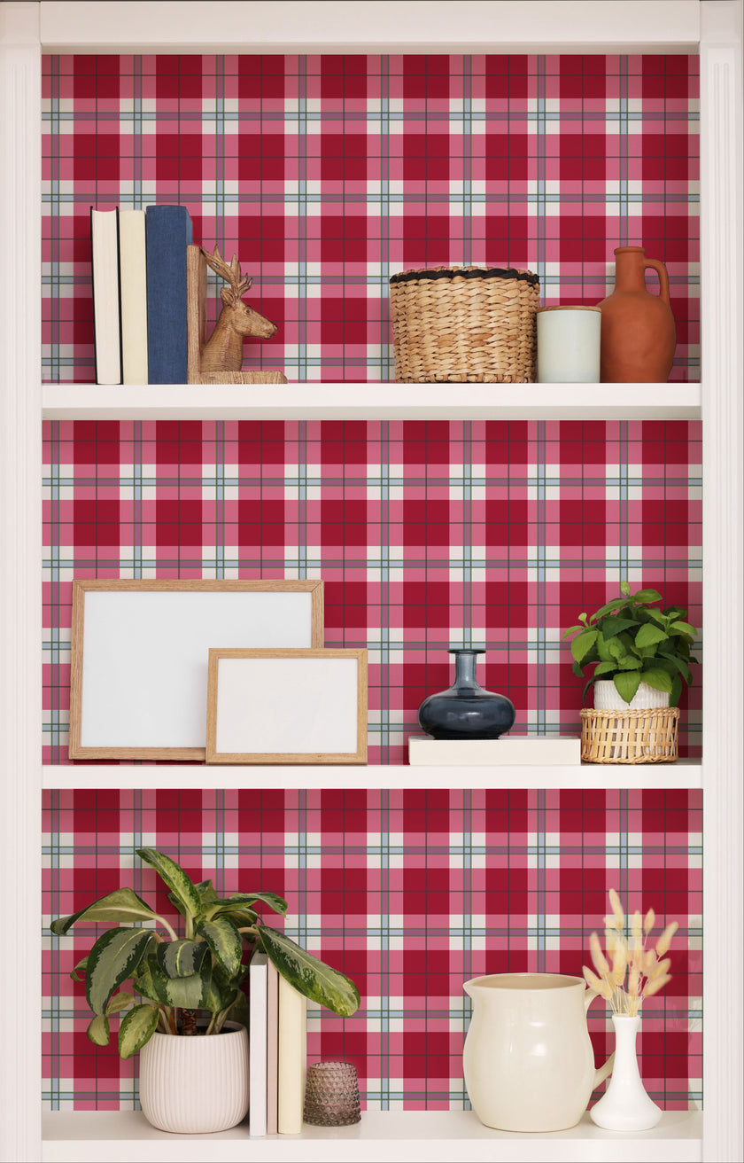 Playful pink tartan wallpaper with layered blush and red tones in a soft check design. Wallpaper behind shelves. 