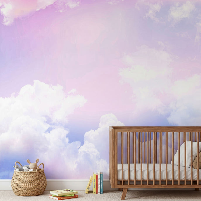 Realistic nursery scene with a playful sky mural in pinks, purples, and blues covering the entire wall, illuminated by soft daylight.