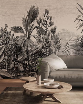 A large scale botanical wall mural featuring detailed black and white palm and tropical foliage, shown behind a grey sofa in a modern living room setting.
