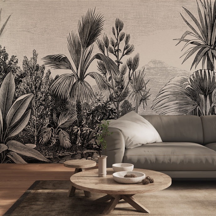 A large scale botanical wall mural featuring detailed black and white palm and tropical foliage, shown behind a grey sofa in a modern living room setting.