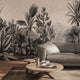 A large scale botanical wall mural featuring detailed black and white palm and tropical foliage, shown behind a grey sofa in a modern living room setting.