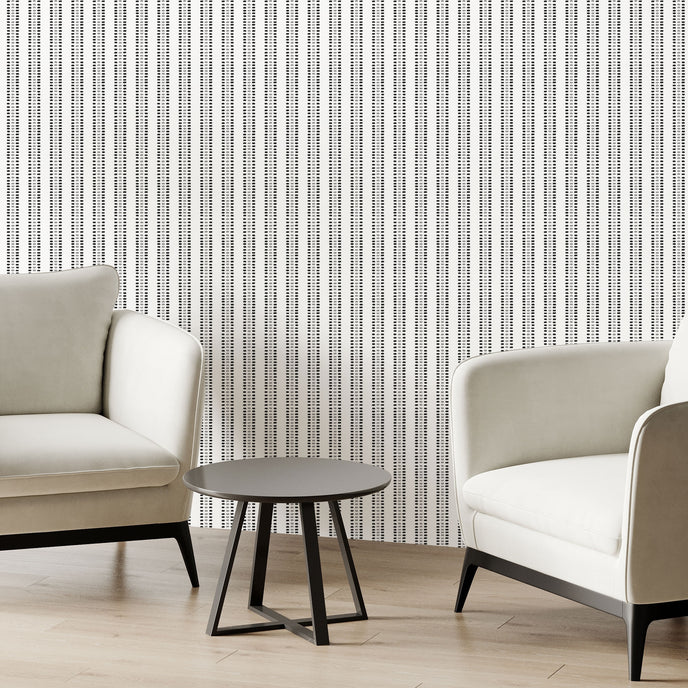 Two modern off white armchairs with black legs and a small round black side table, arranged in a minimalist room with potted plants and Navy and sage green striped wallpaper with organic dashes on a white background.