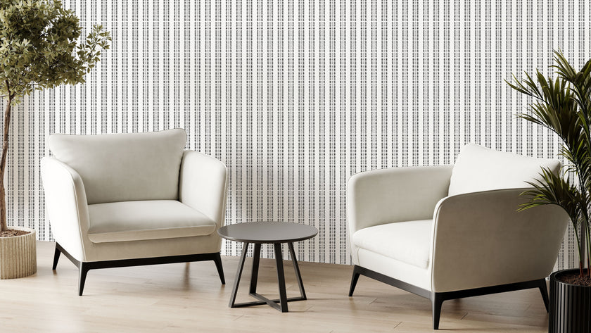 Two modern off white armchairs with black legs and a small round black side table, arranged in a minimalist room with potted plants and Navy and sage green striped wallpaper with organic dashes on a white background.