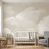Seamless wall mural in a nursery featuring soft beige clouds on a calm sky, scaled to fit the entire wall with natural lighting.