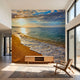 Realistic sunset beach mural filling an entire wall, highlighting ocean textures and vivid sunset colors in a living room.