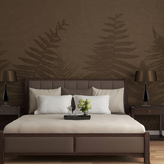 Chocolate brown botanical mural featuring oversized layered fern fronds on a textured brown background. On a wall behind a bed in brown colours with dark wood side tables. 