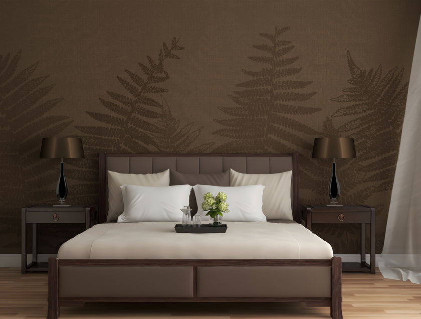 Chocolate brown botanical mural featuring oversized layered fern fronds on a textured brown background. On a wall behind a bed in brown colours with dark wood side tables. 
