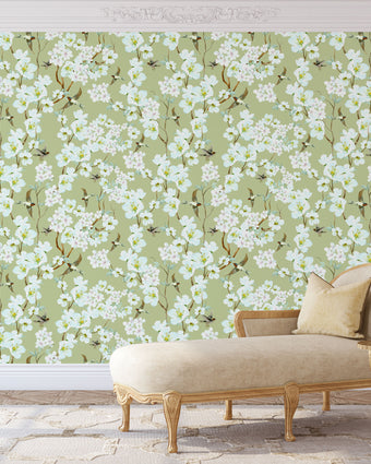 Chinoiserie inspired wallpaper featuring delicate white blossom flowers, flowering branches, and swallows in flight on a soft sage green background.