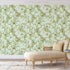 Chinoiserie inspired wallpaper featuring delicate white blossom flowers, flowering branches, and swallows in flight on a soft sage green background.