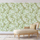 Chinoiserie inspired wallpaper featuring delicate white blossom flowers, flowering branches, and swallows in flight on a soft sage green background.
