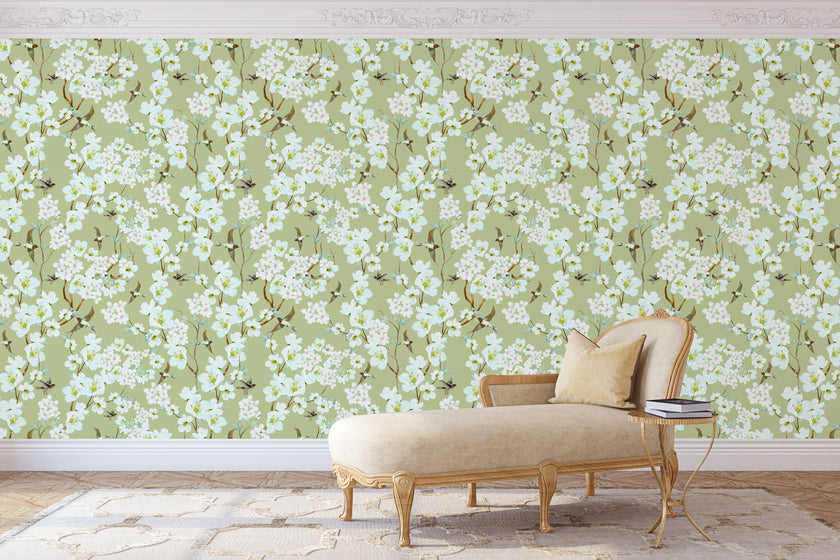 Chinoiserie inspired wallpaper featuring delicate white blossom flowers, flowering branches, and swallows in flight on a soft sage green background.