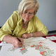 South African botanical artist Gillian Condy painting an illustration of the Sutherlandia frutescens plant, featuring delicate leaves and vibrant orange-red flowers in a detailed naturalistic style.