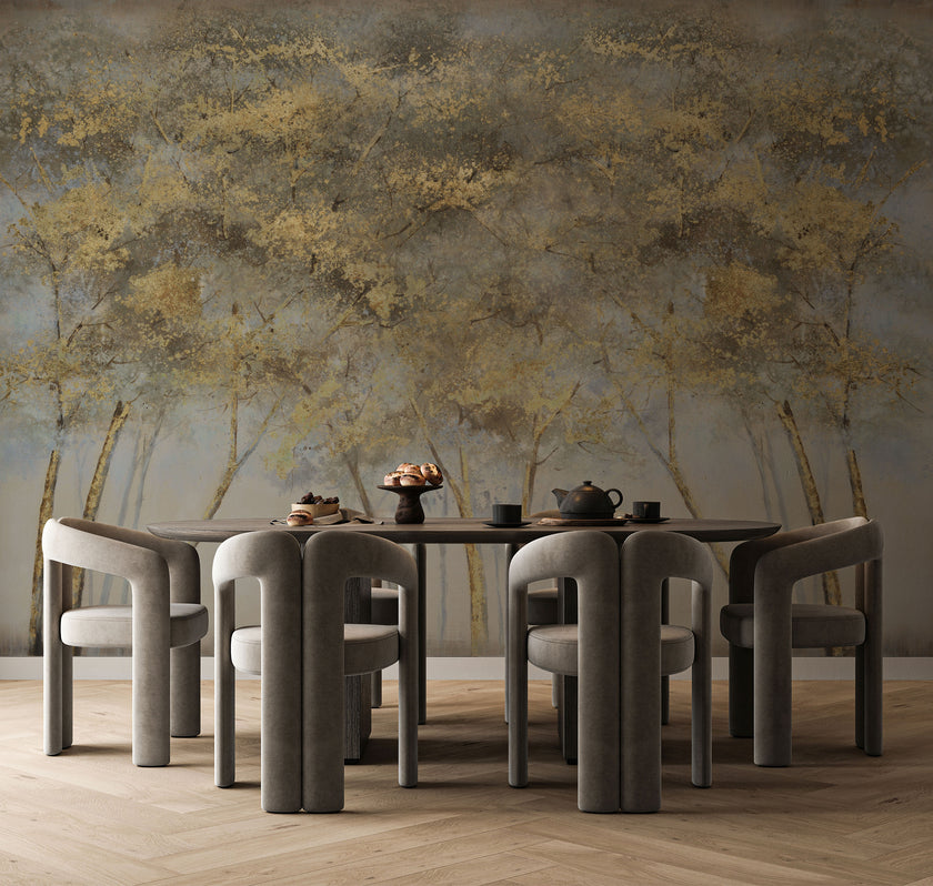 Forest mural featuring golden woodland trees with softly textured foliage against a smoky grey background, creating a warm and atmospheric nature inspired scene. On a wall behind a dinning table with dark furniture. 