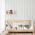 Classic green pinstripe wallpaper with fine vertical stripes, inspired by traditional country house interiors and timeless textile patterns. On kids bedroom wall, behind bed. 