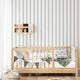 Classic green pinstripe wallpaper with fine vertical stripes, inspired by traditional country house interiors and timeless textile patterns. On kids bedroom wall, behind bed. 