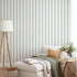 Classic green pinstripe wallpaper with fine vertical stripes, inspired by traditional country house interiors and timeless textile patterns. On lounge/seating area wall, behind couch. 