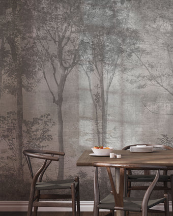 Nature-inspired forest mural featuring misty woodland trees in soft grey tones, creating a calm and atmospheric backdrop for contemporary interiors. On wall in a dinning room, with dark wooden table and chairs. 