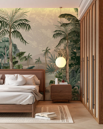 A styled bedroom interior featuring a tropical mural with lush green palms and foliage surrounding a blue lagoon with soft mountains in the background, behind a bed. The room includes a wooden bed frame, white bedding, a matching wooden nightstand with a round white pendant light, a slatted wood wardrobe, and light wood flooring.

