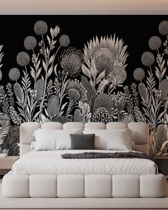 A modern bedroom featuring a large black wall mural with a detailed white botanical and floral pattern behind a low white platform bed.