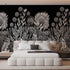A modern bedroom featuring a large black wall mural with a detailed white botanical and floral pattern behind a low white platform bed.