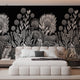 A modern bedroom featuring a large black wall mural with a detailed white botanical and floral pattern behind a low white platform bed.