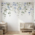 Full view of nursery wall decorated with 'Forget Me Not' floral mural showing seamless pattern on textured surface in natural light.