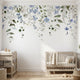 Full view of nursery wall decorated with 'Forget Me Not' floral mural showing seamless pattern on textured surface in natural light.