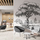 Black and white illustrated mural of a large tree beside a calm river in a peaceful countryside landscape. On a wall in an office seating room. 