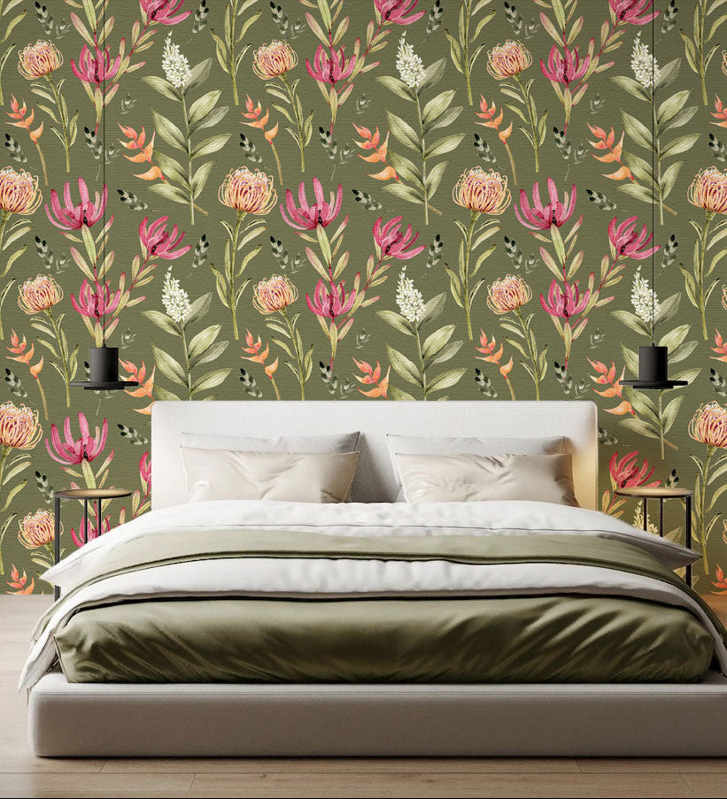 A styled bedroom scene featuring a bed with white and olive bedding in front of a wall covered in a botanical wallpaper with a seamless repeating pattern of hand painted South African fynbos flowers and foliage in blush pink, olive green, and soft neutral tones on an olive background.

