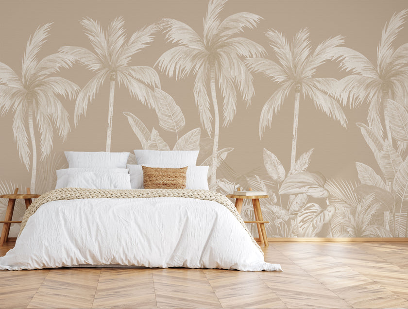 Neutral tropical mural with illustrated palm trees and layered jungle foliage in warm beige and cream inverted tones. On wall behind the bed in white sheets with wooden stool side tables. 