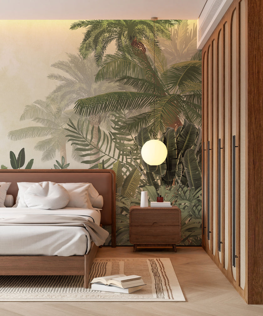 A styled bedroom interior featuring a tropical mural with layered palm trees and lush green foliage on a soft neutral background on the back wall, a wooden bed with white bedding, a matching wooden nightstand and wardrobe, and a round white pendant light.

