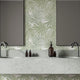 Bathroom featuring Palm Whisper wallpaper with overlapping sage green palm leaves on a white background. The tropical botanical design is displayed behind a double vanity with a marble countertop and two mirrors, creating a fresh coastal inspired space.