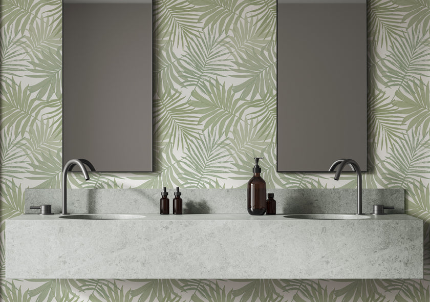 Bathroom featuring Palm Whisper wallpaper with overlapping sage green palm leaves on a white background. The tropical botanical design is displayed behind a double vanity with a marble countertop and two mirrors, creating a fresh coastal inspired space.