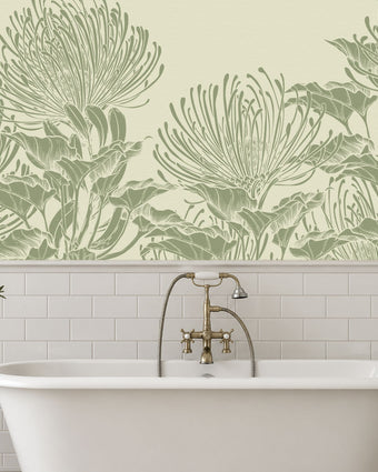 A bathroom scene featuring a white freestanding bathtub with a brass faucet, set against a wall with white subway tiles and a large botanical mural of hand drawn sage green pincushion proteas on a warm ivory background.