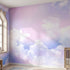 Vibrant sky mural with playful clouds in pinks, purples, and blues covering an entire wall with natural daylight streaming through a stylized window.