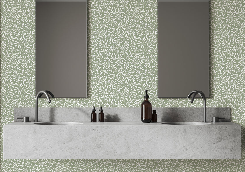 A modern bathroom vanity setup featuring a light grey stone double sink countertop with two dark faucets, two rectangular mirrors, and a sage green botanical wallpaper with a seamless repeat, featuring white leafy sprigs in a simple, elegant pattern.