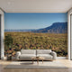 Lifelike mural of towering mountains, flowing river, and green foliage, filling the wall with vivid sky and crisp details.