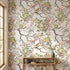Close-up of 'Spring Renewal' mural featuring multicolored birds and floral patterns on textured living room wall, with natural light highlighting details.