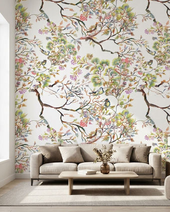 Vibrant floral mural with birds and branches in a bright living room setting, showcasing scale and detailed botanical pattern.
