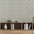 A styled interior scene showing a light wood media console against a wall with a sage grey botanical wallpaper with a seamless repeat, featuring ivory hand-drawn leaves and flowing stems with delicate dotted detailing. Decorative bowls, books, and vases sit on and inside the console.


