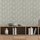 A styled interior scene showing a light wood media console against a wall with a sage grey botanical wallpaper with a seamless repeat, featuring ivory hand-drawn leaves and flowing stems with delicate dotted detailing. Decorative bowls, books, and vases sit on and inside the console.

