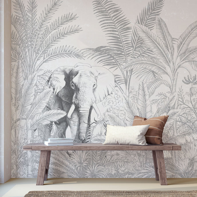 Hand-drawn tropical mural featuring an elephant surrounded by palm trees and dense botanical foliage in soft grey tones. Placed on a wall in a walkway, with a wooden bench in front on the mural.