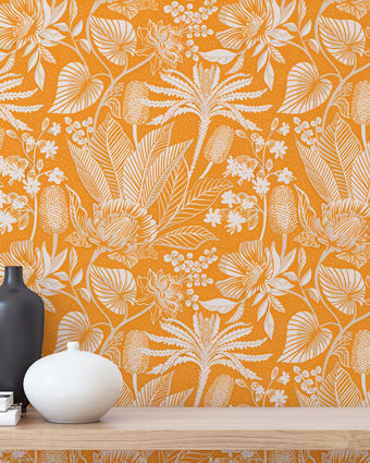 Apricot colour wallpaper with white floral pattern, wooden shelf with decor items.