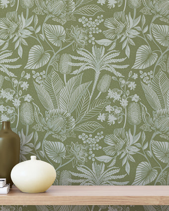 Floral green wallpaper with a wooden shelf and decorative items in the foreground